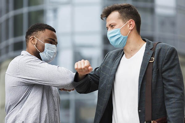 Dos colegas se tocan los codos al aire libre durante la pandemia